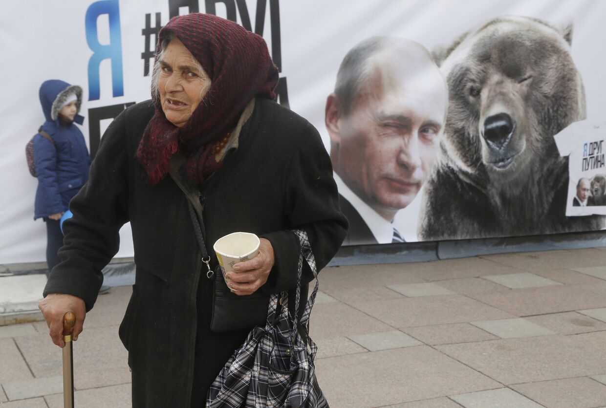 Пожилая женщина на фоне плаката с Владимиром Путиным в Санкт-Петербурге