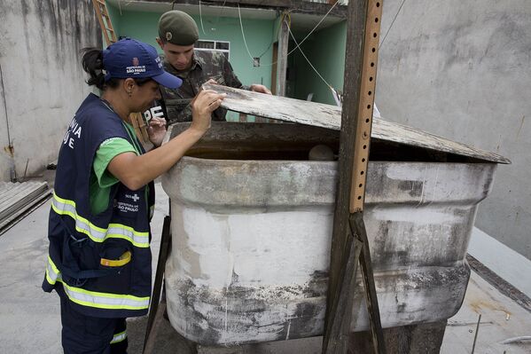 Медицинский работник и солдат проверяют контейнер в рамках операции по уничтожению комаров вида Аedes Аegypti, переносящих вирус Зика