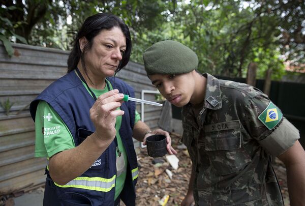 Медицинский работник показывает солдату личинки комаров вида Аedes Аegypti