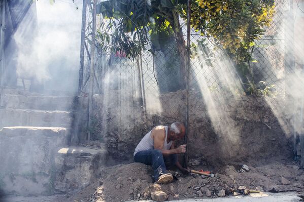 Мужчина работает среди облака инсектицидов, распыленных городскими службами для борьбы с комарами вида Аedes Аegypti, переносящих вирус Зика