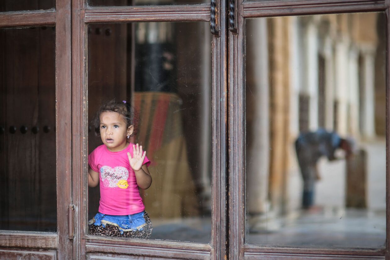 Девочка смотрит на мужчину, умывающегося после службы в местной мечети