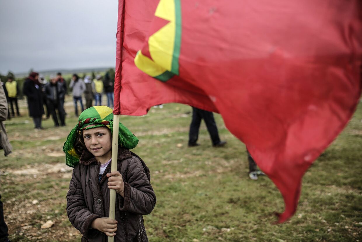Мальчик из семьи сирийских курдов держит флаг Курдистана во время празднования Навруза в городе Кобани