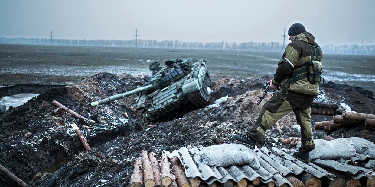 Ополченец стоит у танка украинской армии в Донецкой области