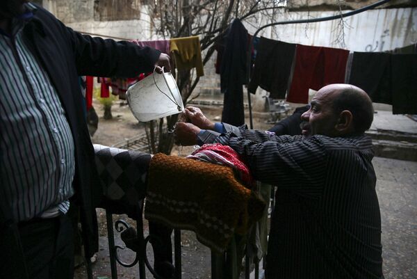 Инвалид Шахрур моет руки возле своего дома, Ирбин, Сирия