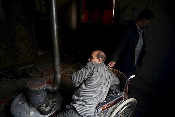 Инвалид Шахрур с ампутированной ногой и диабетом старается забраться в свое кресло, Ирбин, Сирия