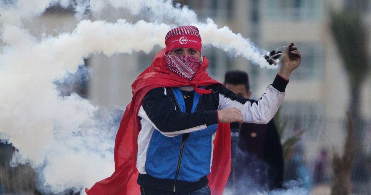 Палестинцы кидают баллончики со слезоточивым газом во время столкновений с израильскими солдатами