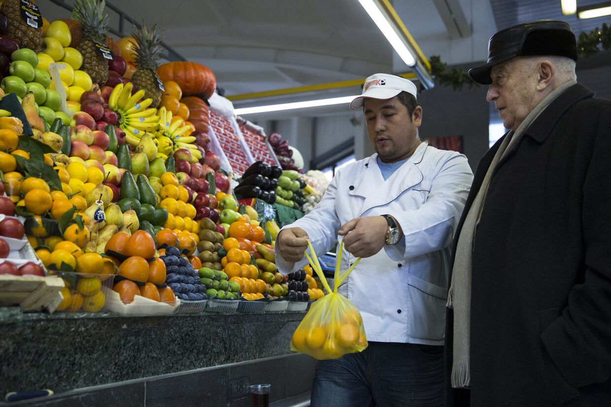 Мужчина покупает мандарины на рынке в Москве