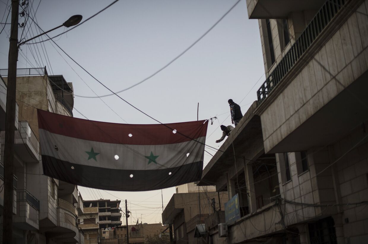 Бойцы Соторо вывешивают флаг Сирии на одной из улиц в городе Камышли провинции Эль-Хасаке на северо-востоке Сирии