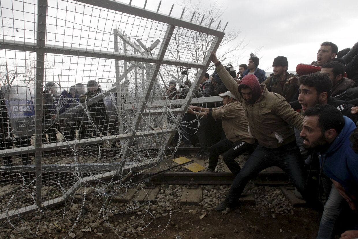 Беженцы и мигранты пытаются сломать часть забора во время протестов на границе Греции и Македонии