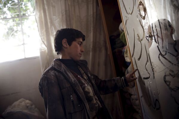 Мальчик рисует пальцем на пыльном зеркале в разрушенном доме