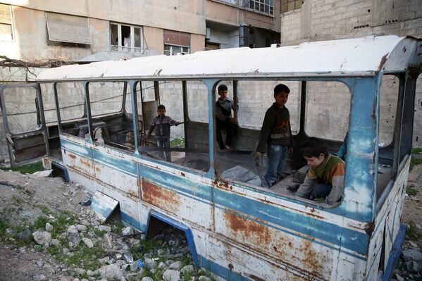 Дети играют в разбитом школьном автобусе в пригороде Дамаска