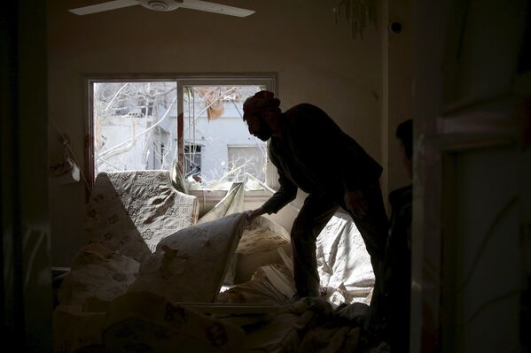 Мужчина ищет свои вещи в одном из домов в пригороде Дамаска