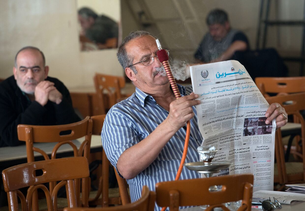 Посетитель кальянной в Дамаске читает газету