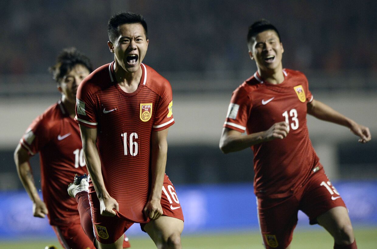 Футболисты Китайской соборной по футболу радуются забитому голу в матче со сборной командой из Катара