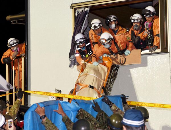Спасатели выносят женщину из разрушенного в результате землетрясения дома. Кумамото, Япония. Апрель 2016