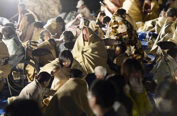 Местные жители сидят в одеялах на дороге после землетрясения. Кумамото, Япония. Апрель 2016