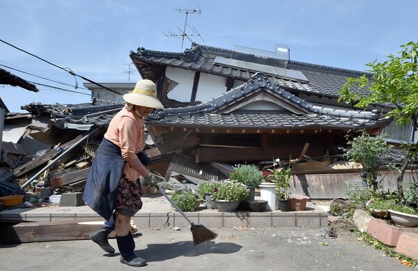 Женщина у своего разрушенного в результате землетрясения дома. Кумамото, Япония. Апрель 2016