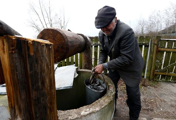 Житель зоны отчуждения Чернобыльской АЭС набирает воду из колодца