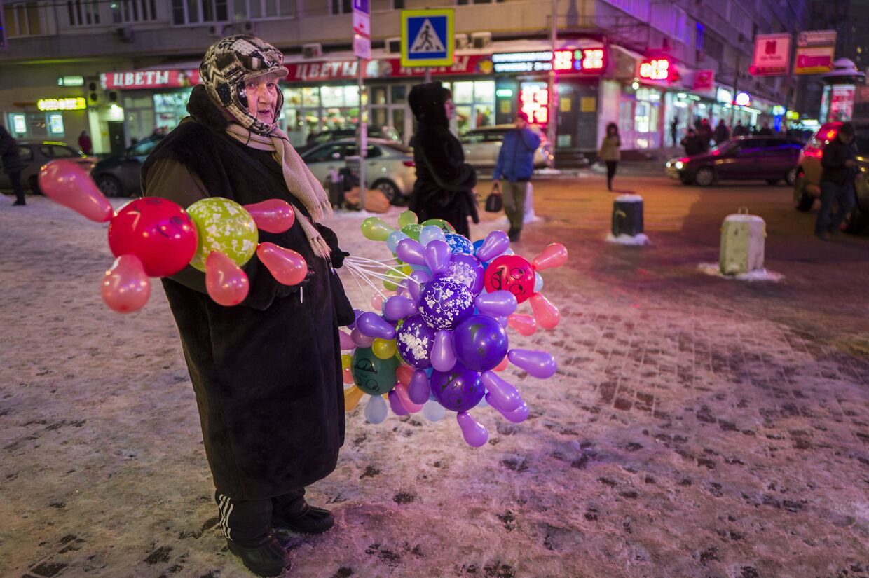 Пожилая женщина продает цветные шары в центре Москвы