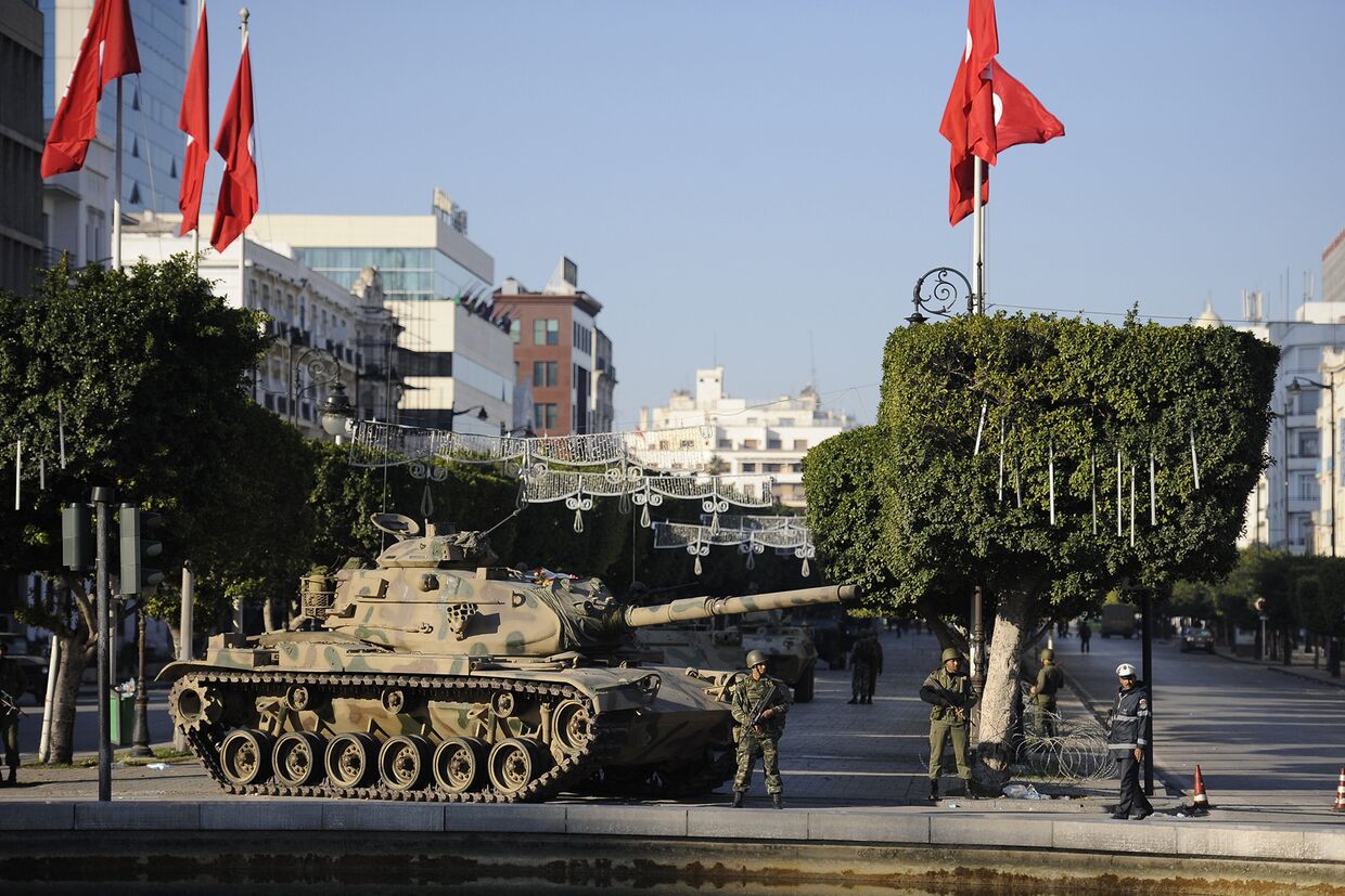 Солдаты стоят возле танка на улице Туниса
