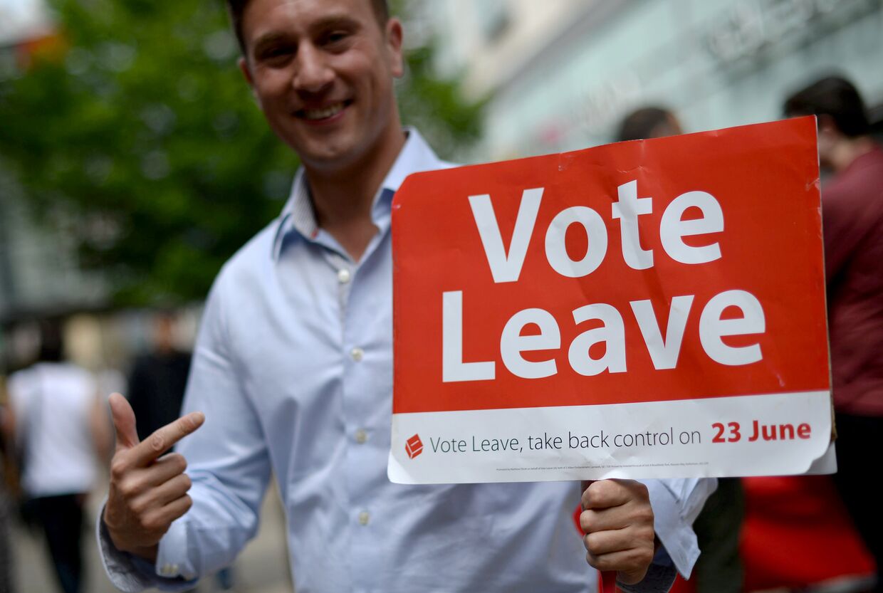 Волонтер на улице Манчестера с агитационным плакатом за выход Великобритании из ЕС