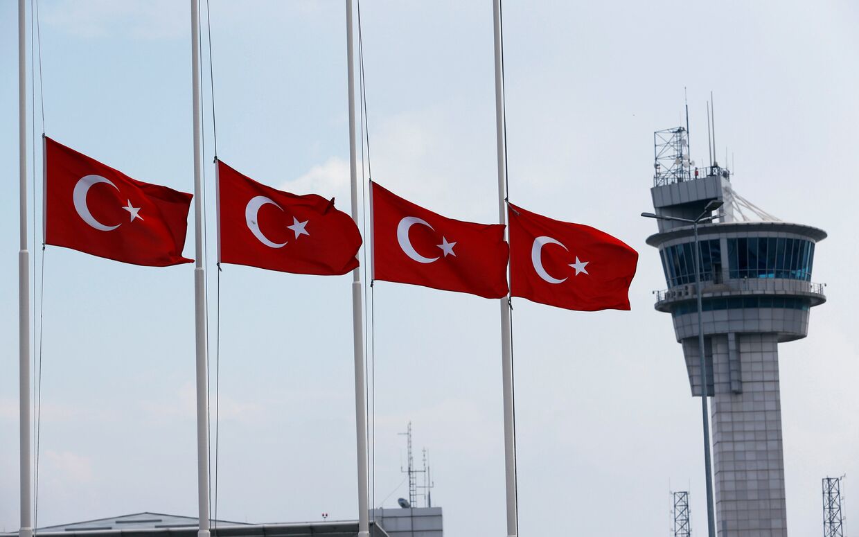 Приспущенные турецкие флаги на фоне вышки в аэропорту имени Ататюрка в Стамбуле, Турция. 29 июня 2016