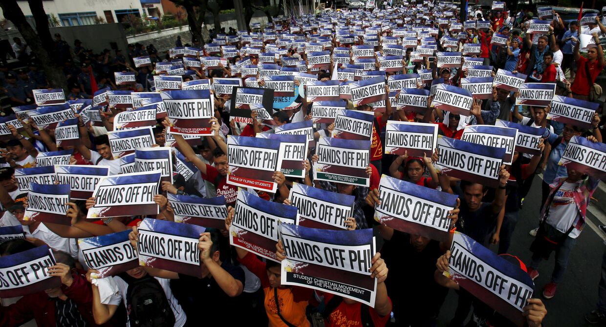Активисты держать плакаты с надписью Руки прочь от Филлипин! во время акции протеста по спорам в Южно-Китайском море