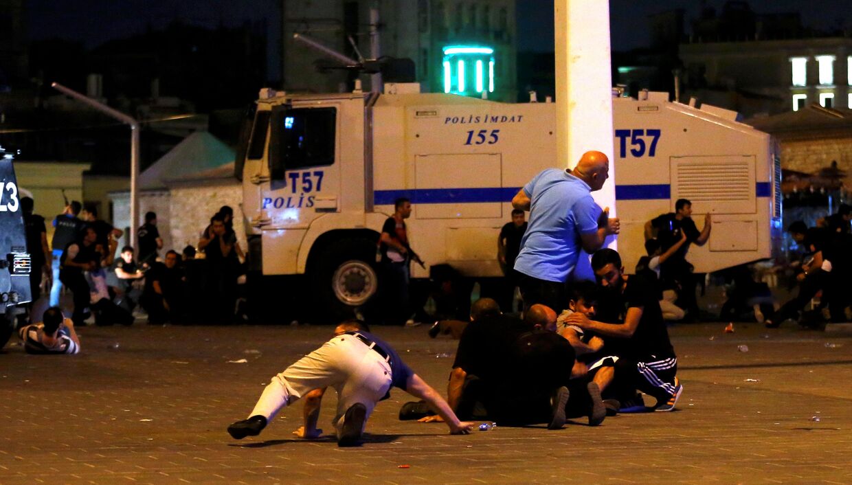 Люди прячутся от стрельбы на площади Таксим в Стамбуле. 16 июля 2016