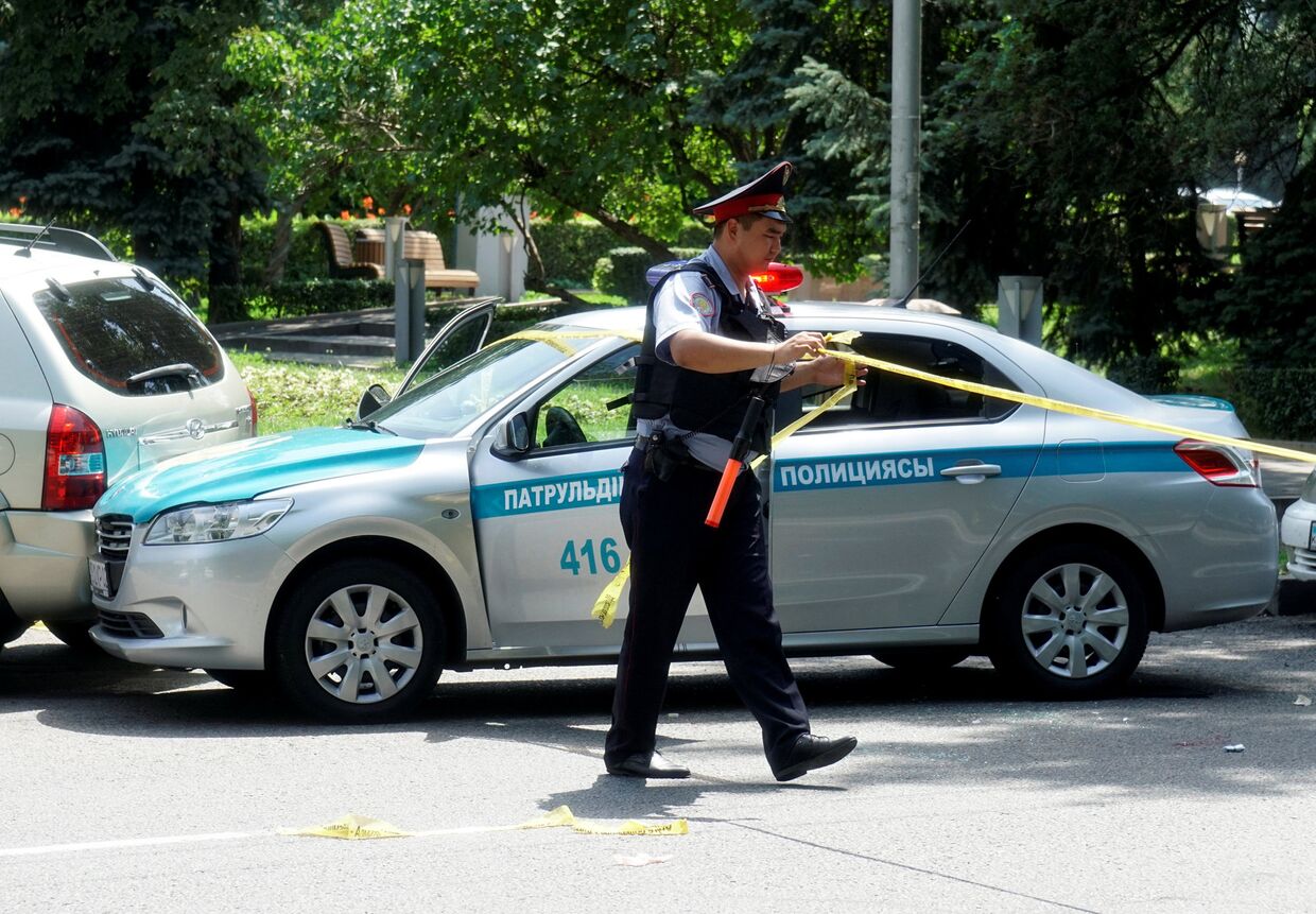 Полицейский огораживает место преступления на улице в Алма-Ате