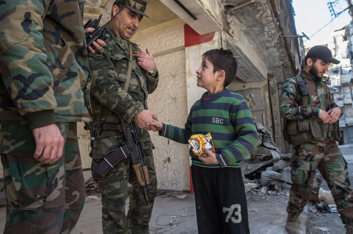 Мальчик общается с военнослужащими Сирийской Арабской армии в жилом квартале города Алеппо