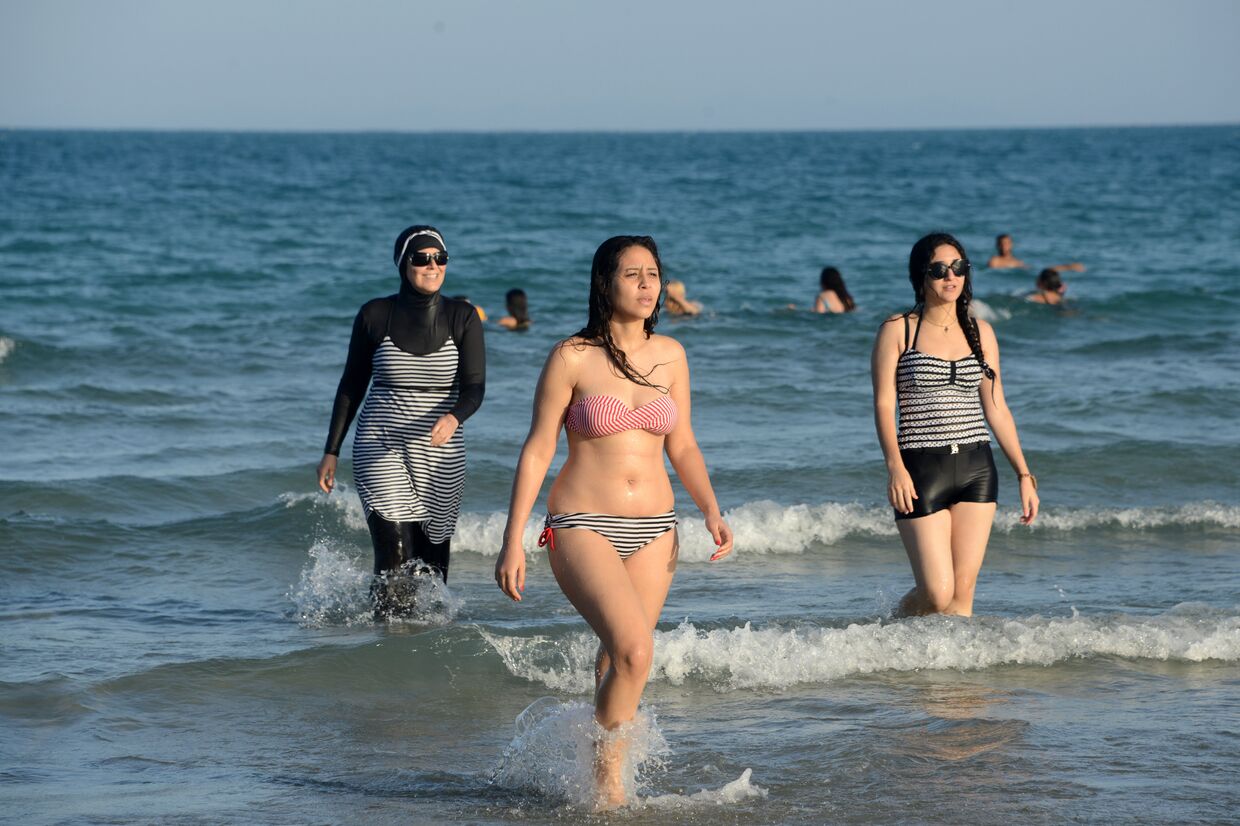 Девушки в буркини и бикини на пляже в Тунисе