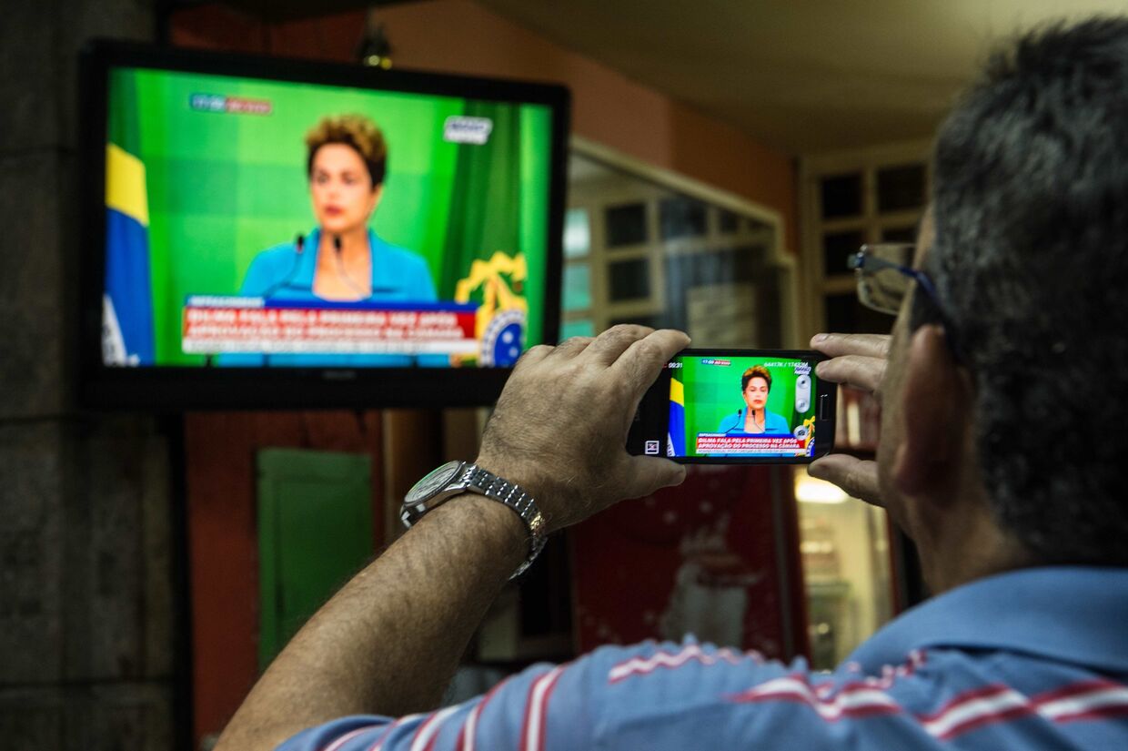 Мужчина записывает выступление по бразильскому телевидению временно отстраненной от должности Дилмы Роуссефф