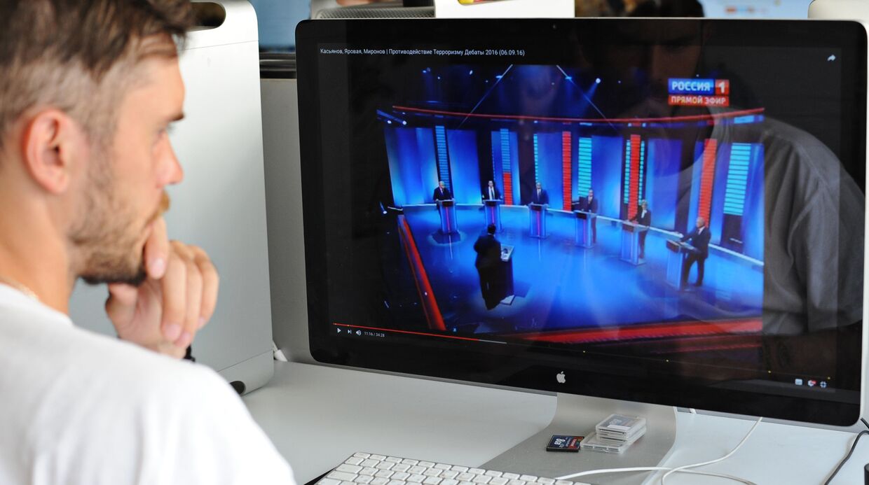 Молодой человек смотрит предвыборные теледебаты с экрана монитора