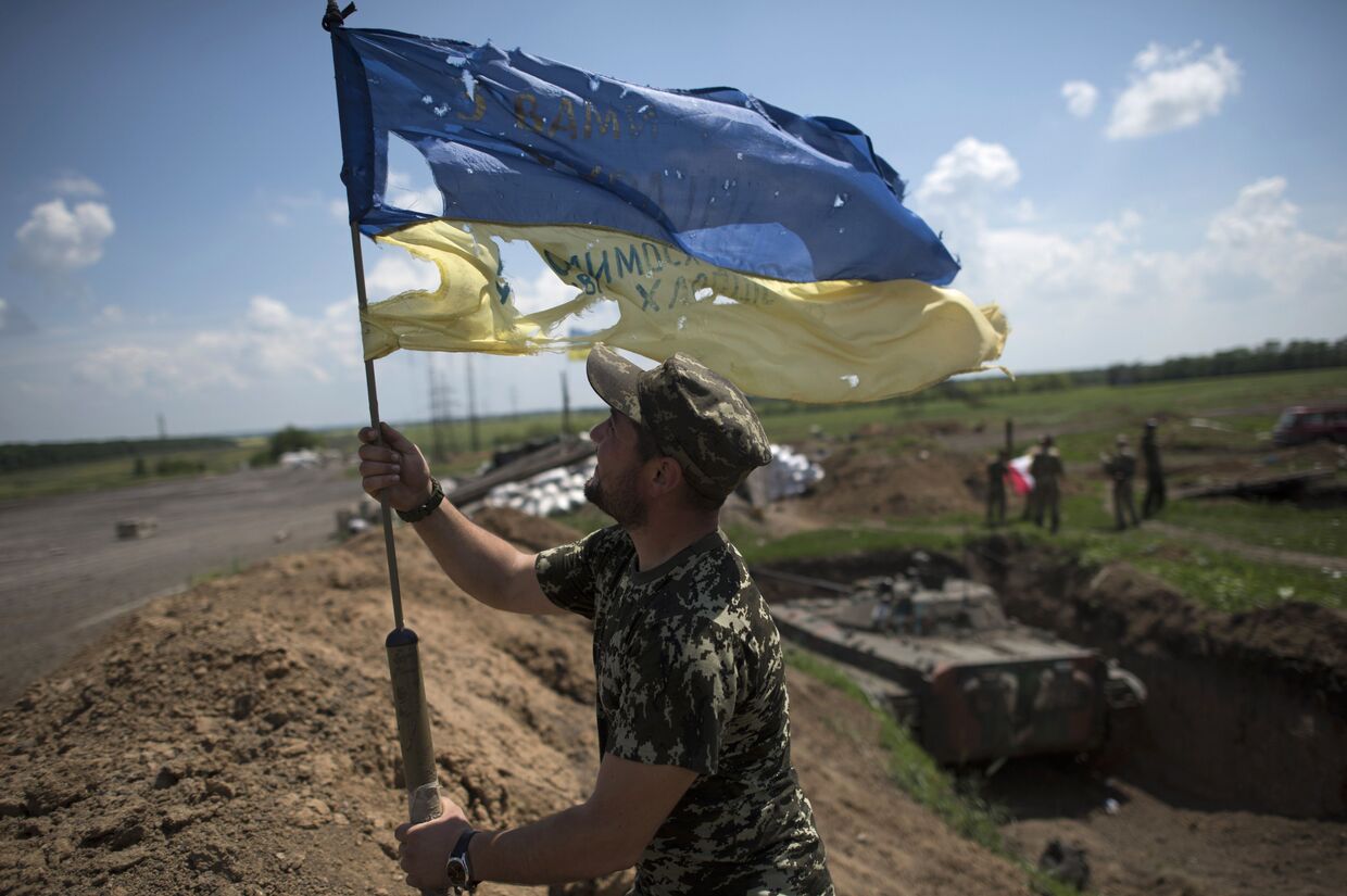 Украинский военный устанавливает флаг Украины в Марьинке недалеко от Донецка