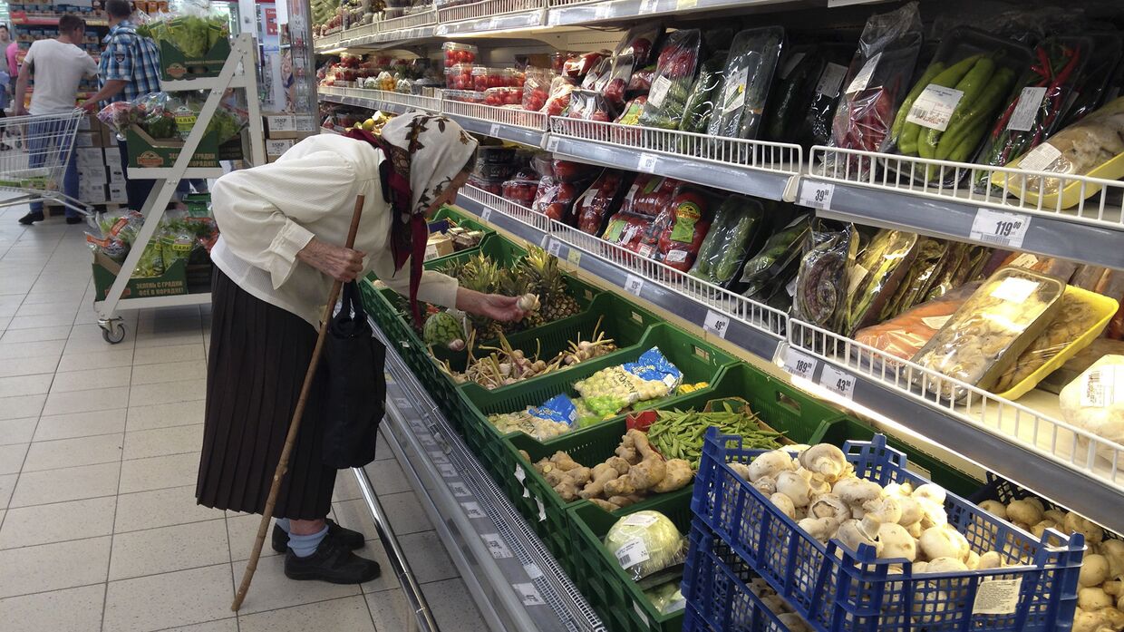 Пожилая женщина выбирает овощи в супермаркете в Дмитрове
