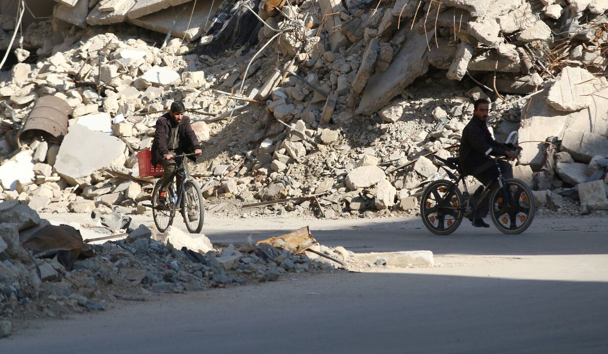 Местные жители среди завалов разрушенных зданий в Алеппо