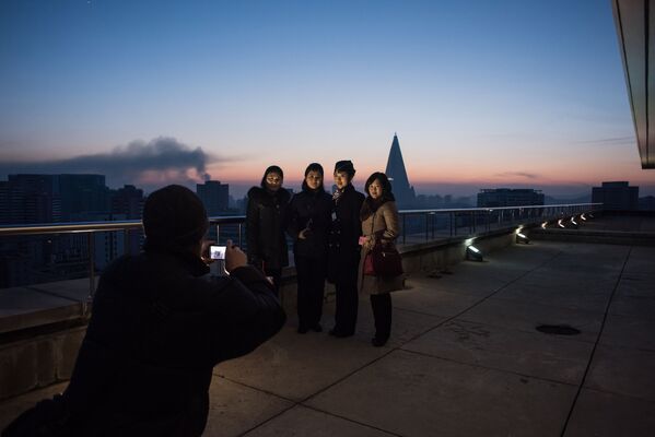 Туристы позируют для фото на вершине Триумфальной арки в Пхеньяне