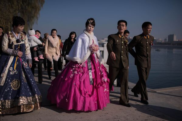 Жених и невеста с родственниками и друзьями ругяют на берегу реки Тэдон в Пхеньяне