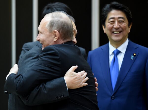Президент России Владимир Путин обнимается с бывшим премьер-министром Японии Ёсиро Мори