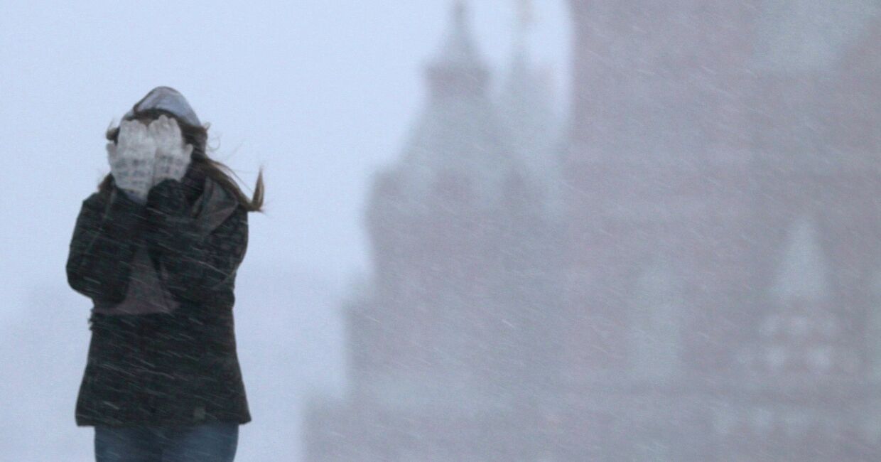 Девушка закрывает лицо от снега во время метели. Архивное фото