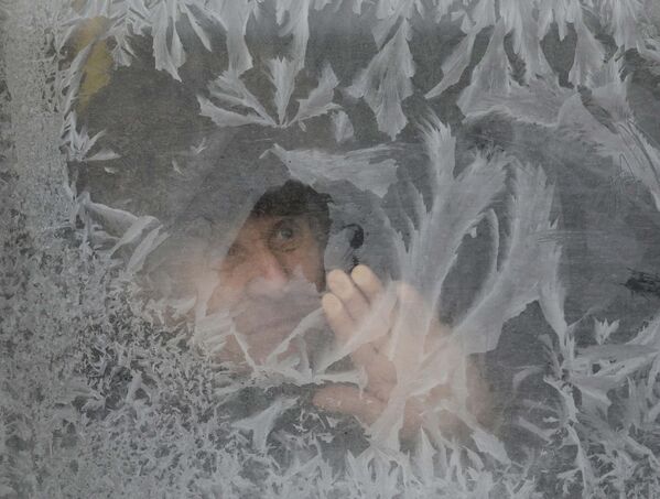 Мужчина смотрит в замороженное окно автобуса в Львове