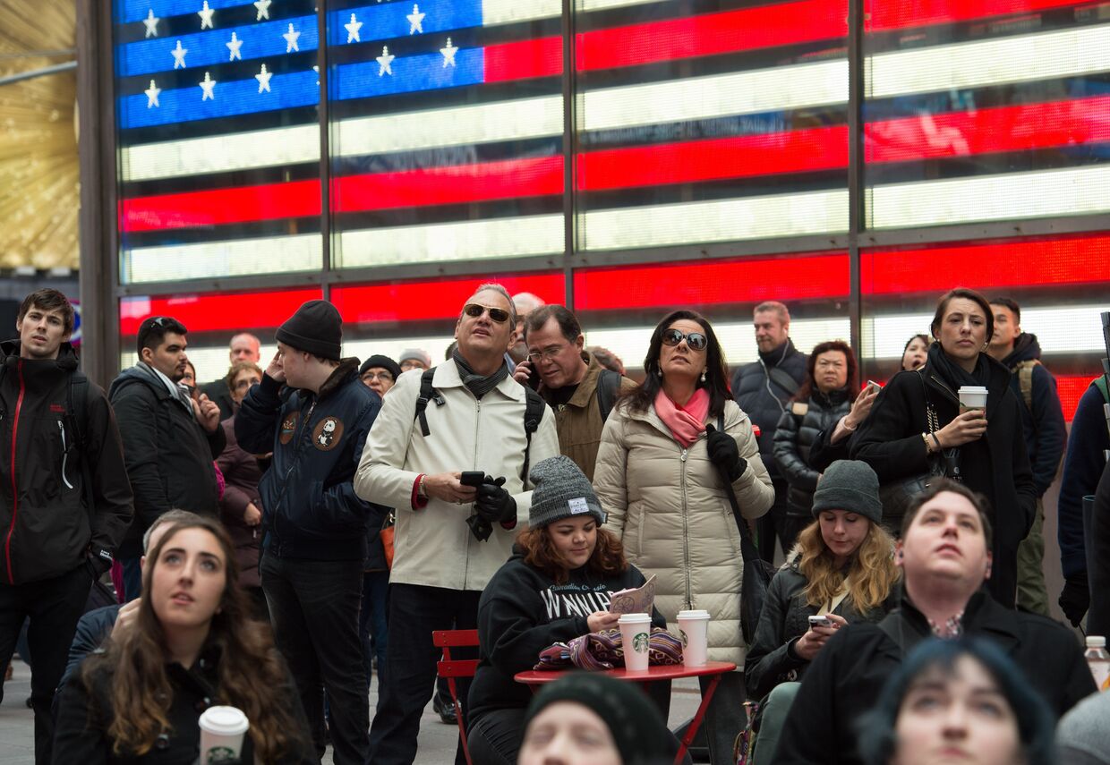 Люди смотрят трансляцию инаугурации Дональда Трампа на Таймс-сквер в Нью-Йорке. 20 января 2017 года