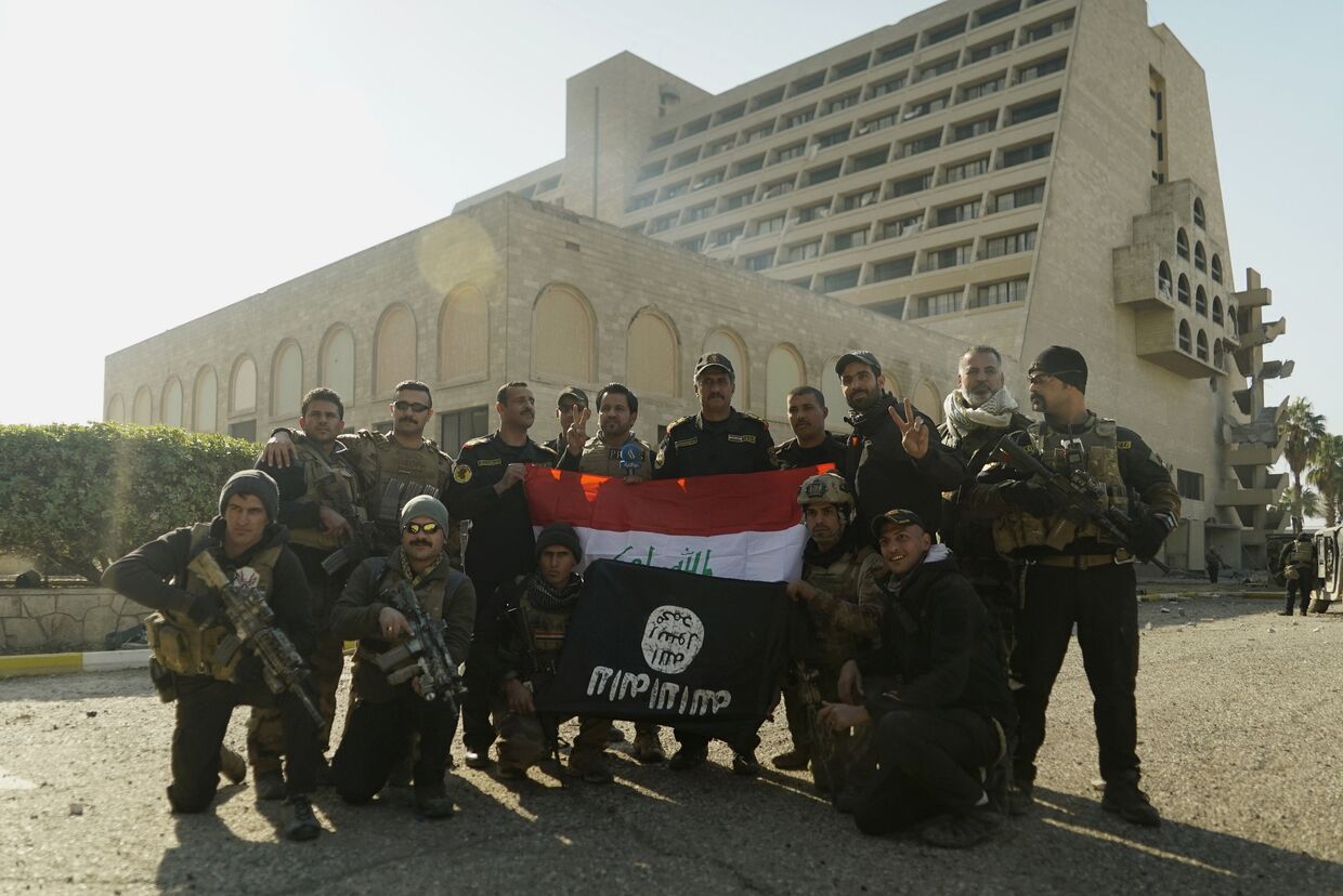 Иракские спецназовцы позируют с национальным флагом и захваченным боевиками ИГИЛ напротив гостиницы Nineveh
