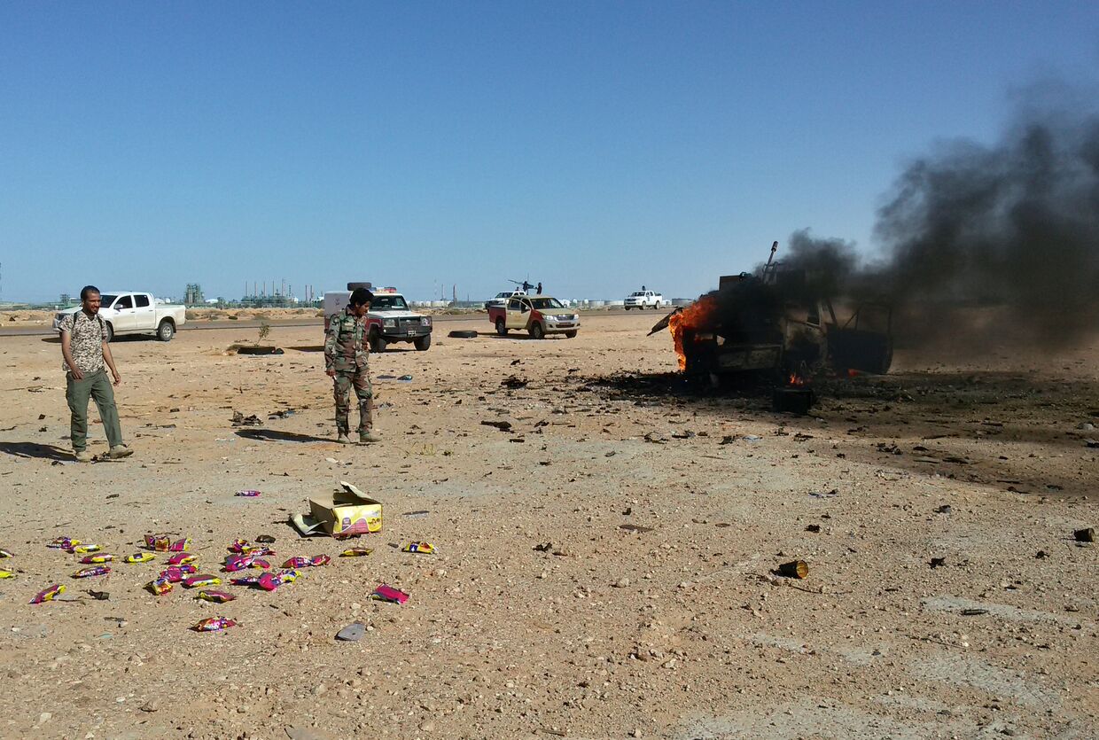 Горящий автомобиль после столкновений между ливийской армией и бойцами «Бригады обороны Бенгази» в Ливии