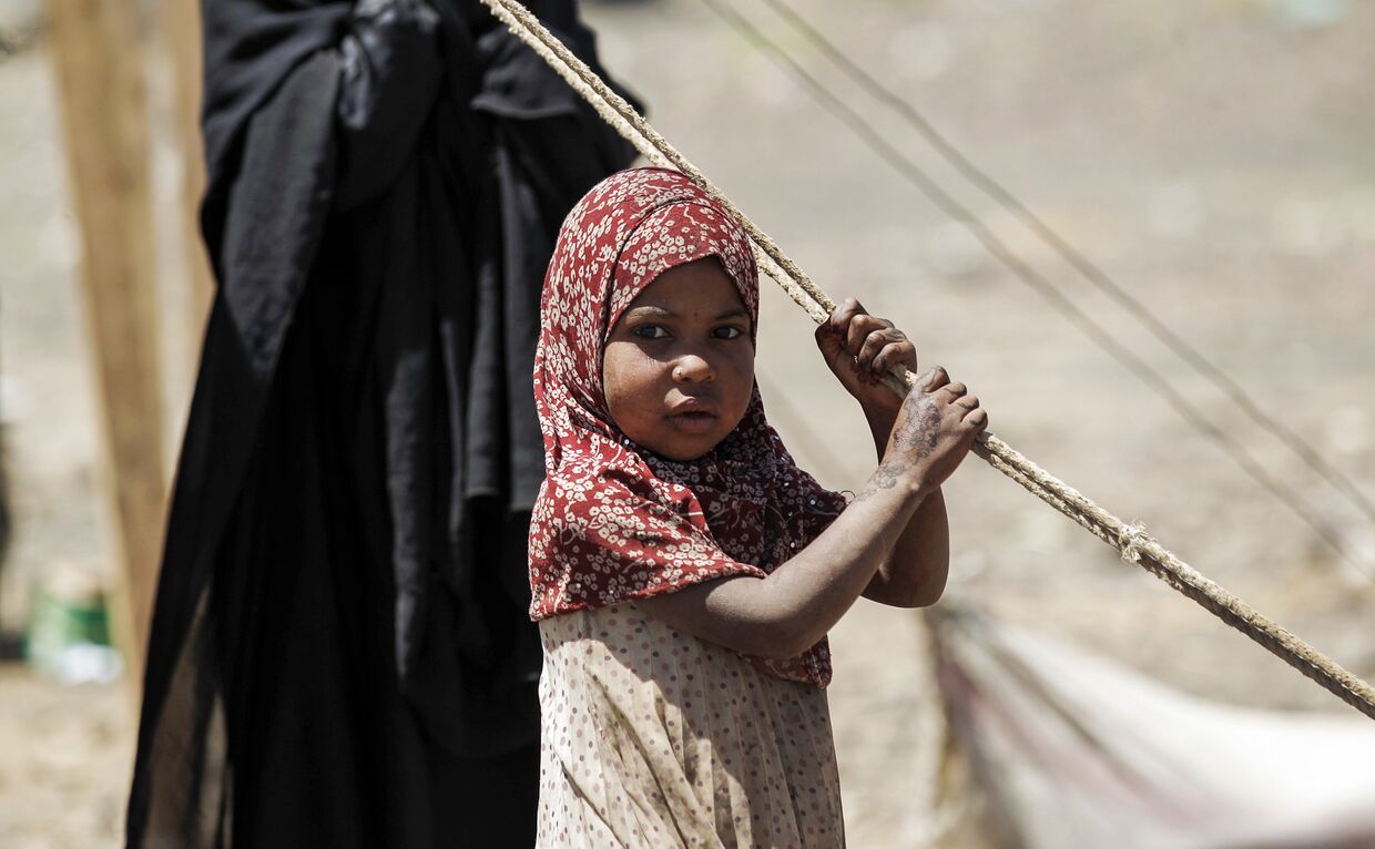 Йеменская девочка ждет поставки гуманитарной помощи российской гуманитарной миссии в лагере на окраине столицы Саны