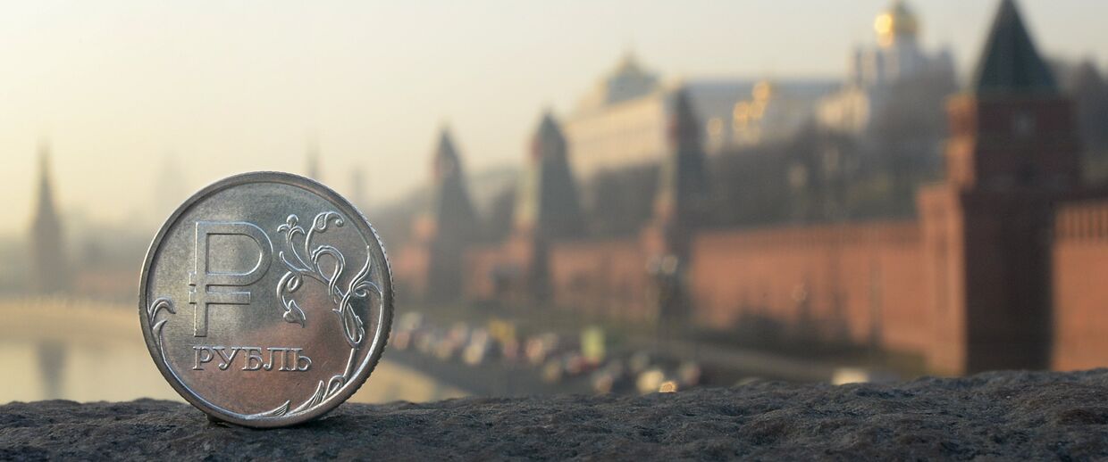 Рублевая монета на фоне Московского Кремля