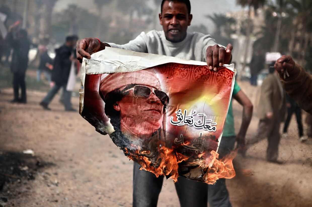 Житель Бенгази сжигает портрет Муамара Каддафи