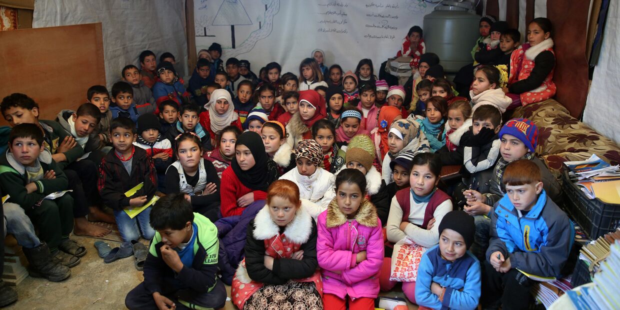 Сирийские беженцы слушают учителя в импровизированной школе в лагере для беженцев в городе Каб Элиас, Ливан