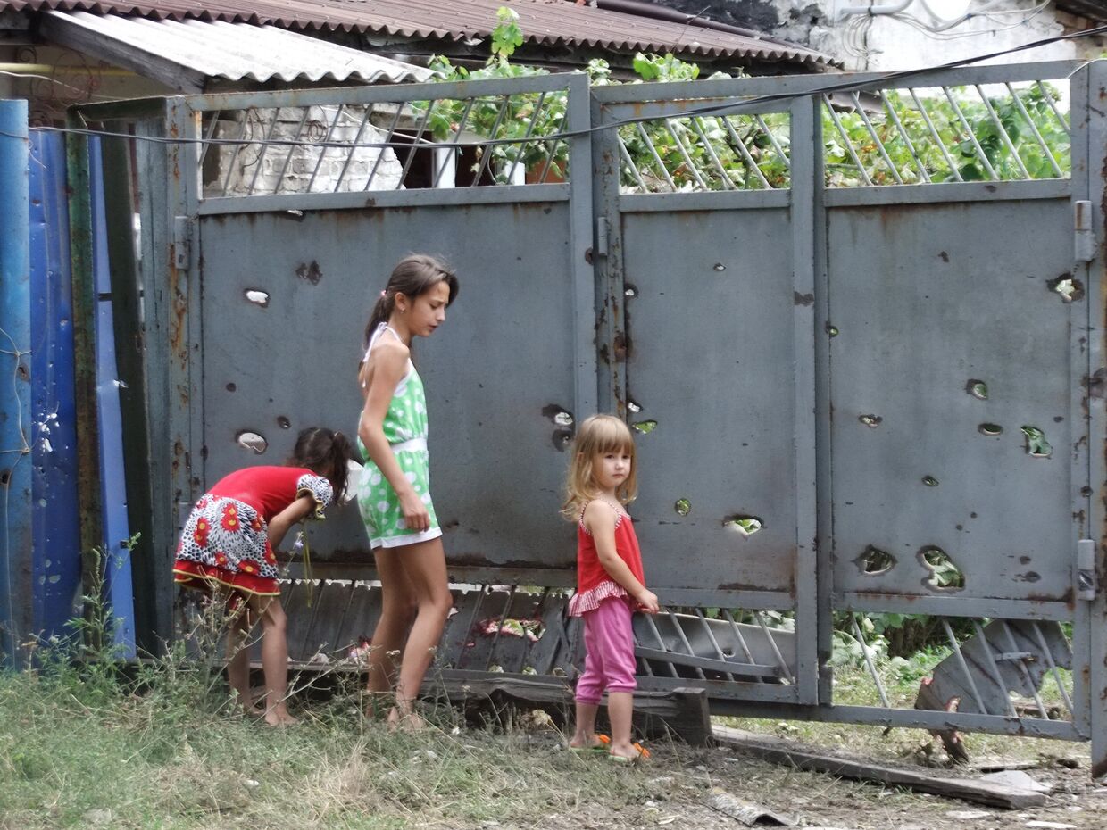 Дети у ворот, поврежденных осколками в результате обстрела украинских силовиков