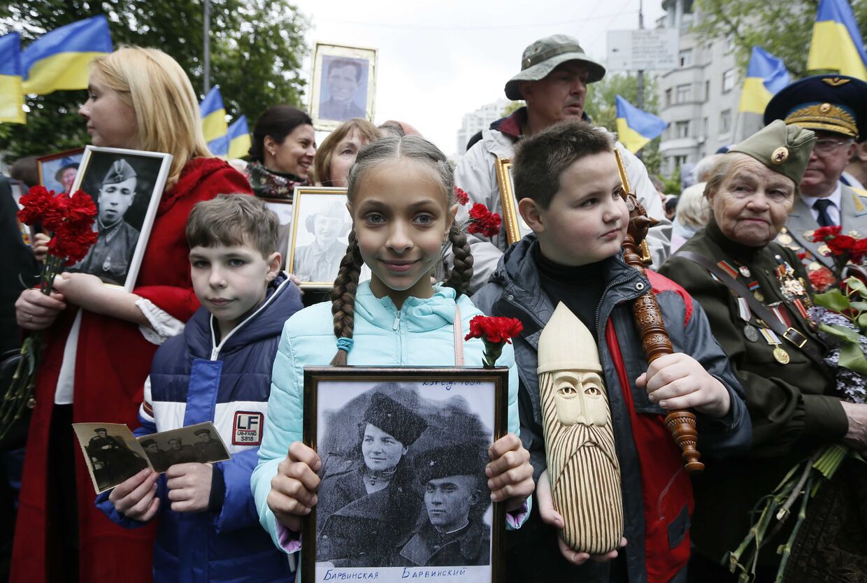 9 мая 2017 года. Участники «Бессмертного полка» в Киеве несут фотографии солдат Второй мировой войны во время празднования 72-й годовщины победы над фашистской Германией.